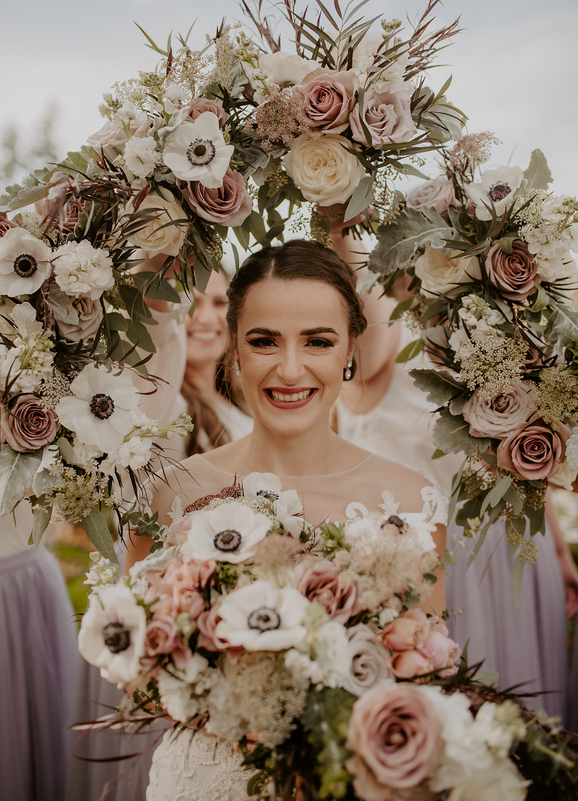 The bridesmaids using their bouquets to create a flower halo around the bride