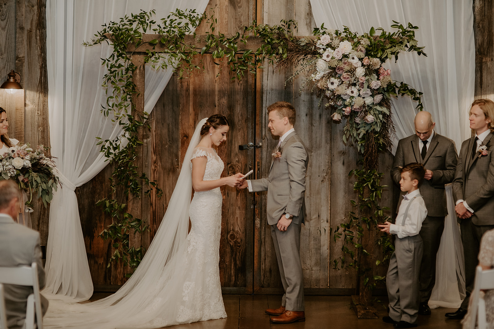 Bride and groom saying vows in front of floral arch