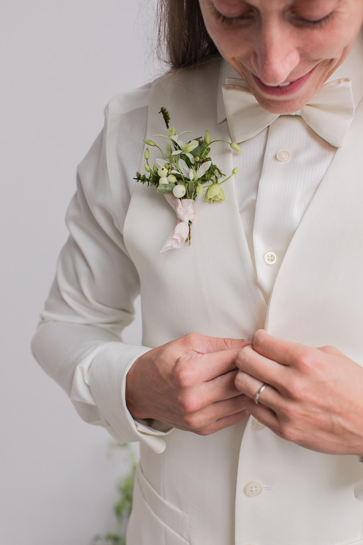 Modern-White-Wedding-Boutonniere-and-Vest A bride with a boutonniere buttoning up a white vest