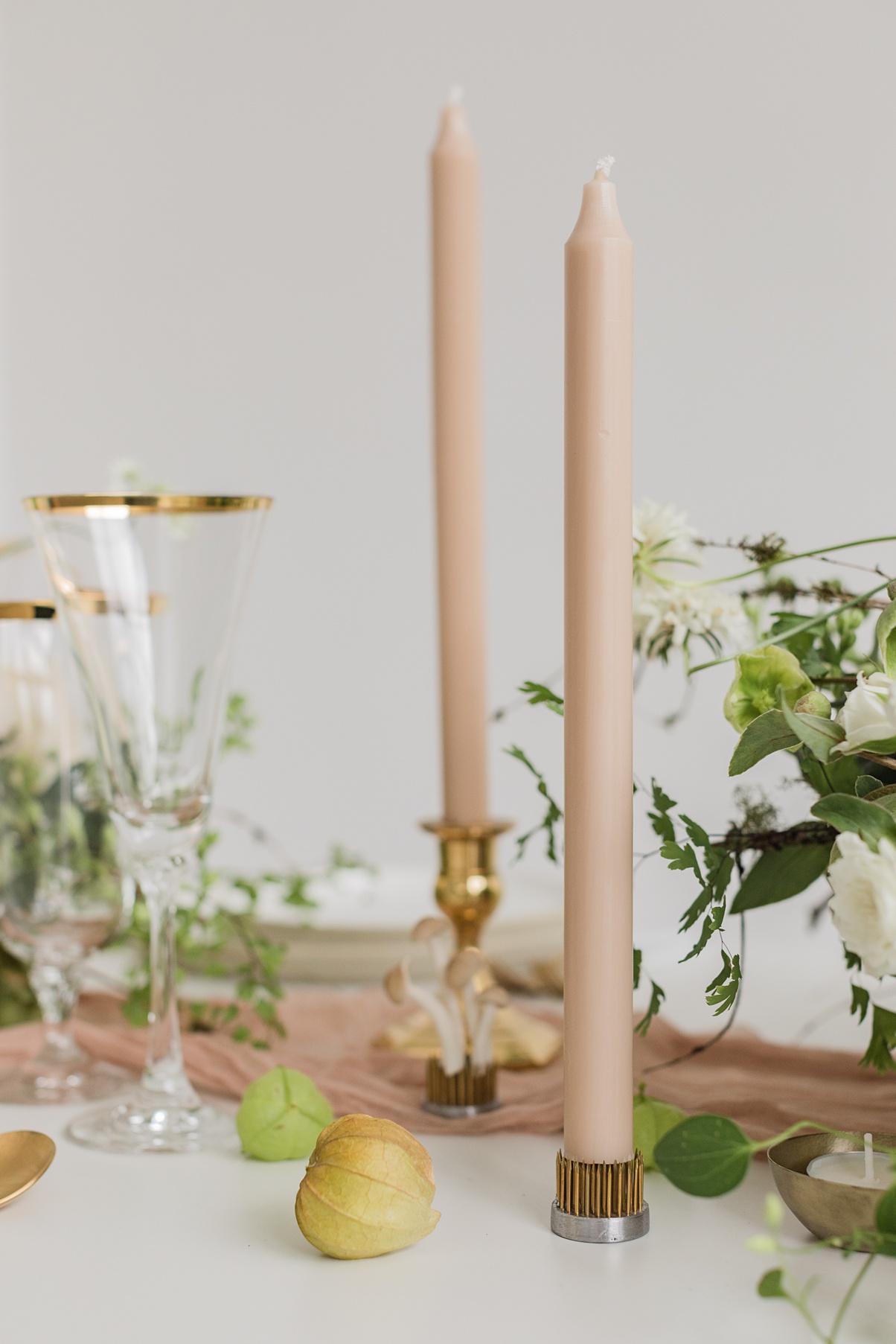 Modern-White-Wedding-Candles-and-Mushrooms A white table with tan taper candles and mushrooms
