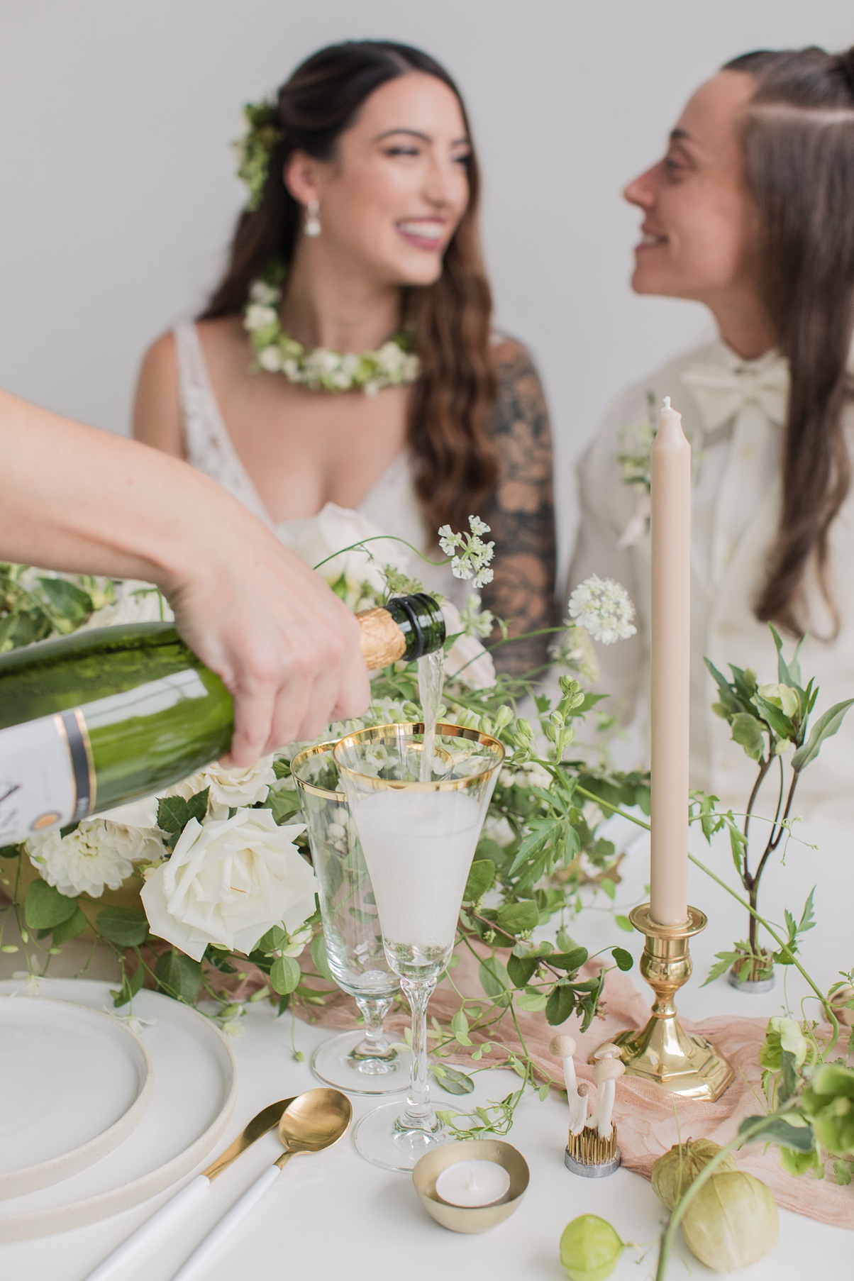 Modern-White-Wedding-Champagne-Pour Champagne being poured as brides look at each other lovingly