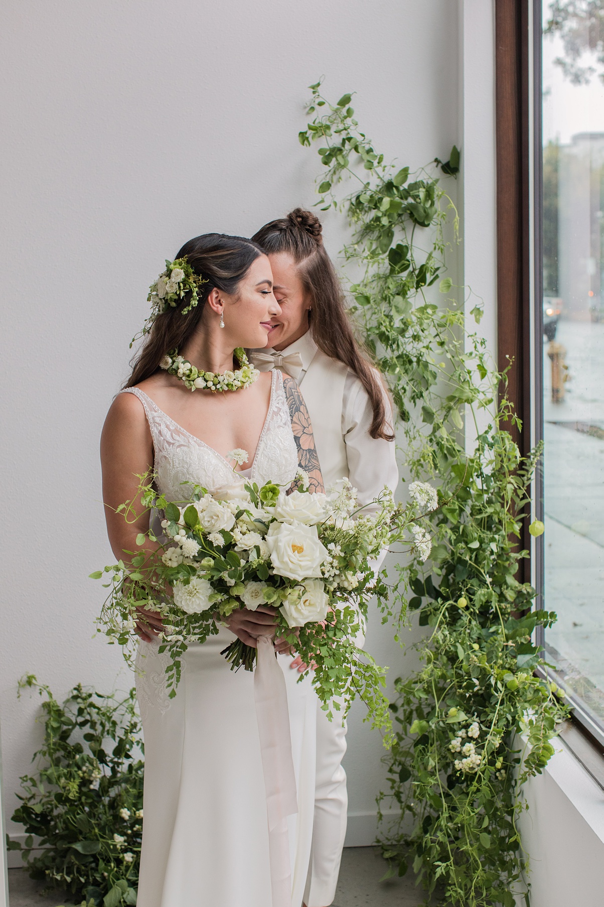 Modern-White-Wedding-Couple-Embracing-by-Window Brides embracing and holding white bouquet