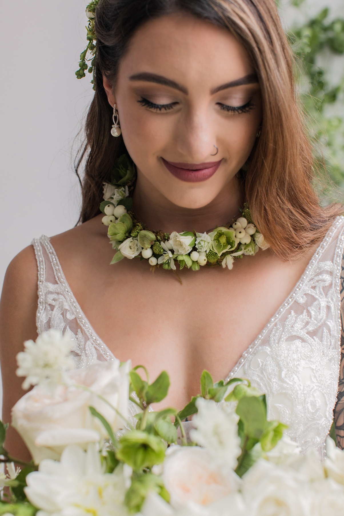 Modern-White-Wedding-Floral-Necklace-Wearable-Flowers A bride holding a bouquet and wearing a floral necklace