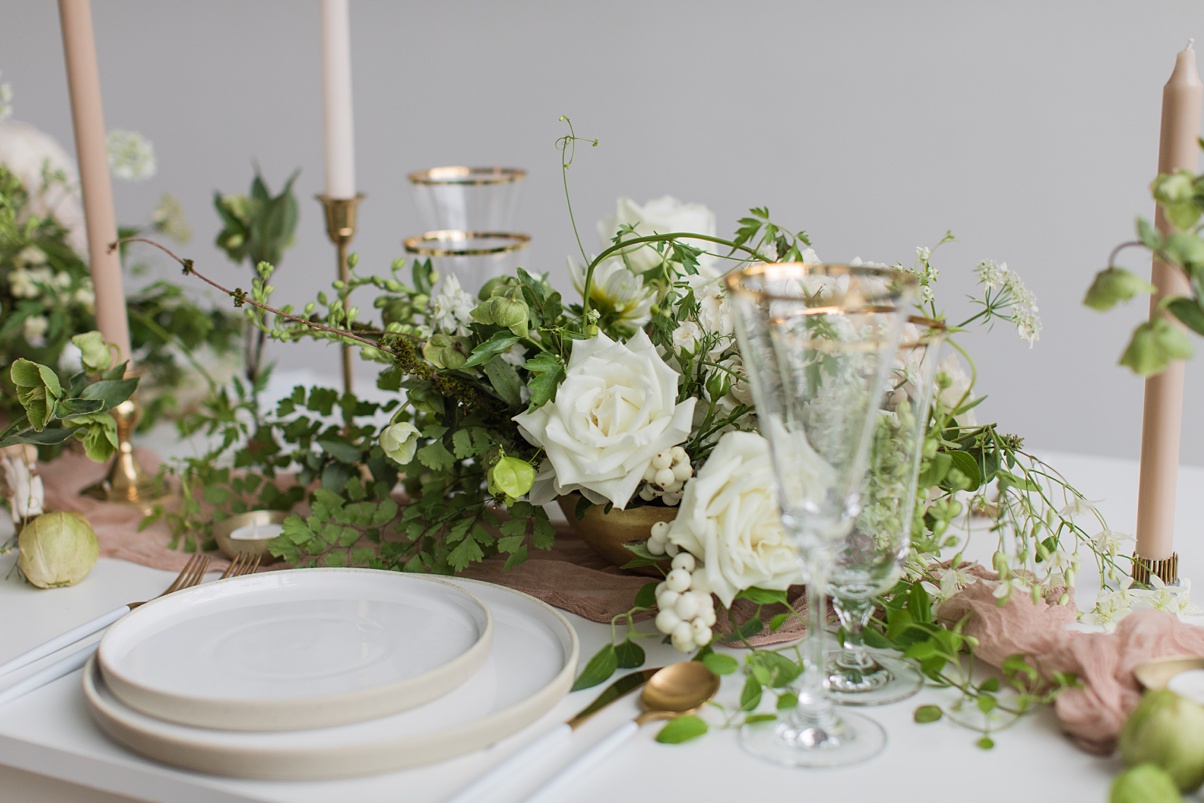 Modern-White-Wedding-Table-Settings Table settings with stoneware plates, white floral arrangements, and tan taper candles