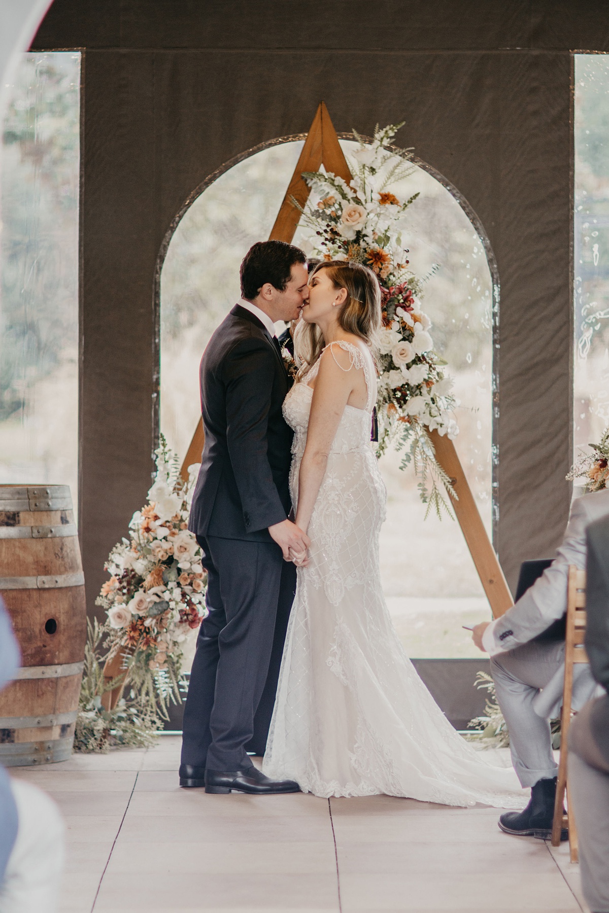 the couples first kiss at the garden gazebo tent, in front of their ceremony arch