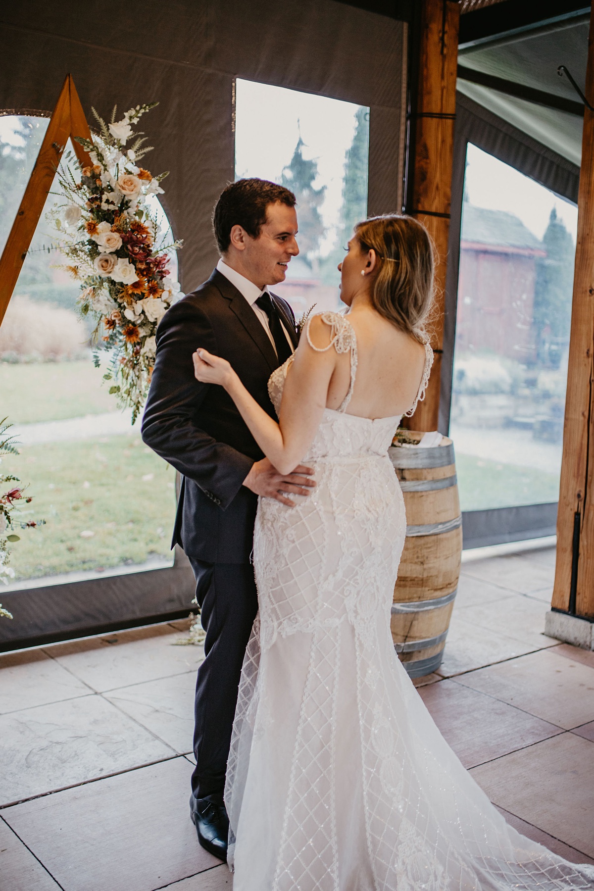 the bride and groom embracing in front of the floral arch for their first look