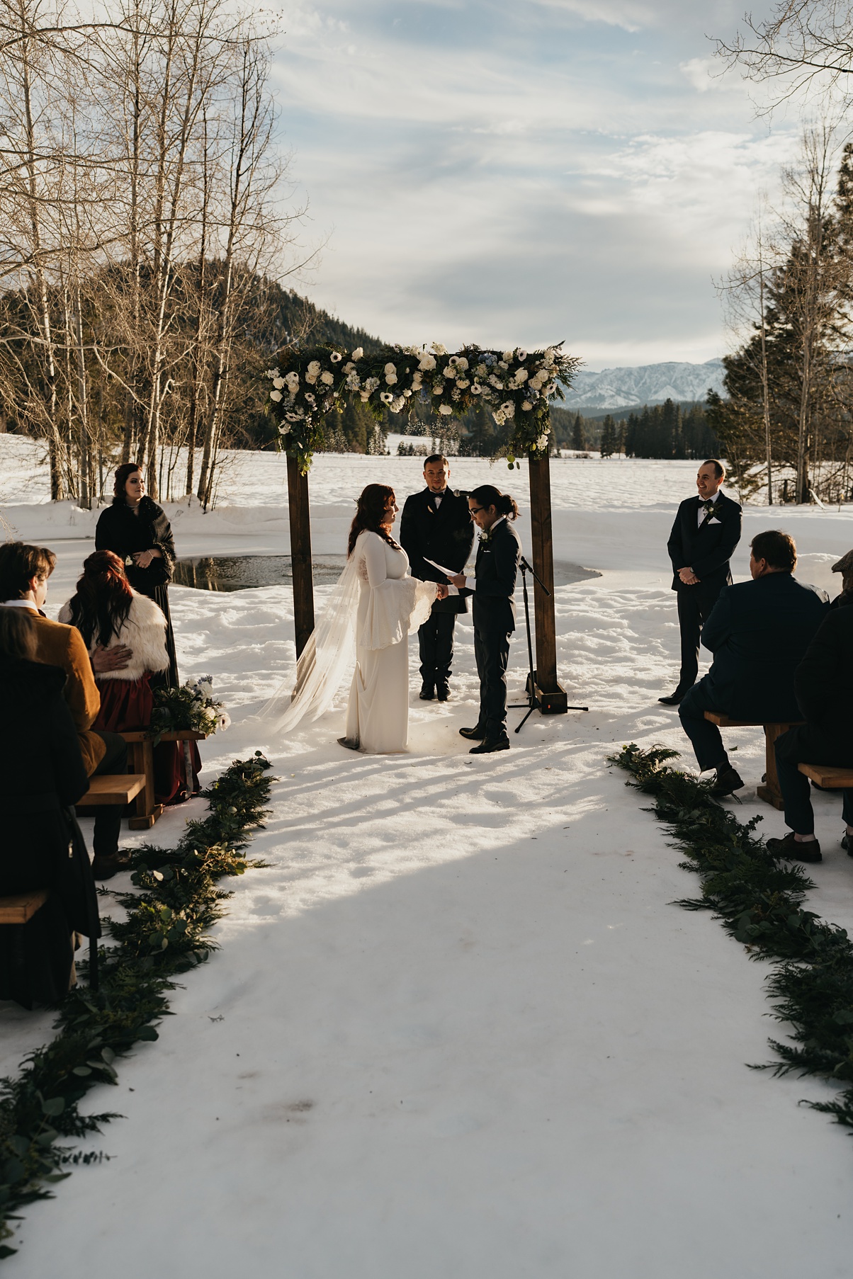 Winter-Destination-Wedding-Mountain-Springs-Lodge-Ceremony The couple standing at their wedding ceremony with mountains in the background