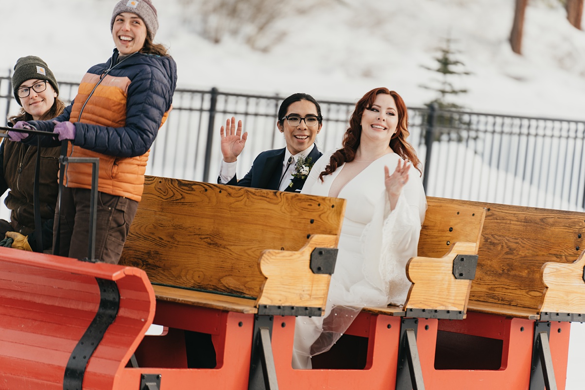 The happy couple waving from their sleigh ride