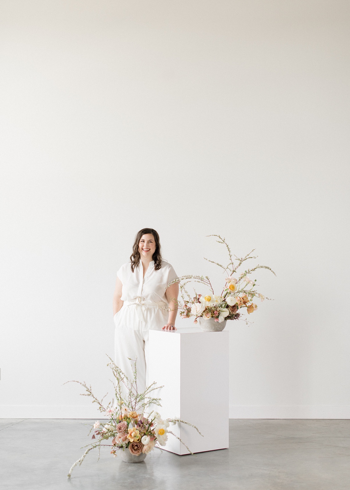 Carolyn-Kulb-Bloom-Poet-Blog Owner Carolyn Kulb standing next to floral arrangements on a pillar
