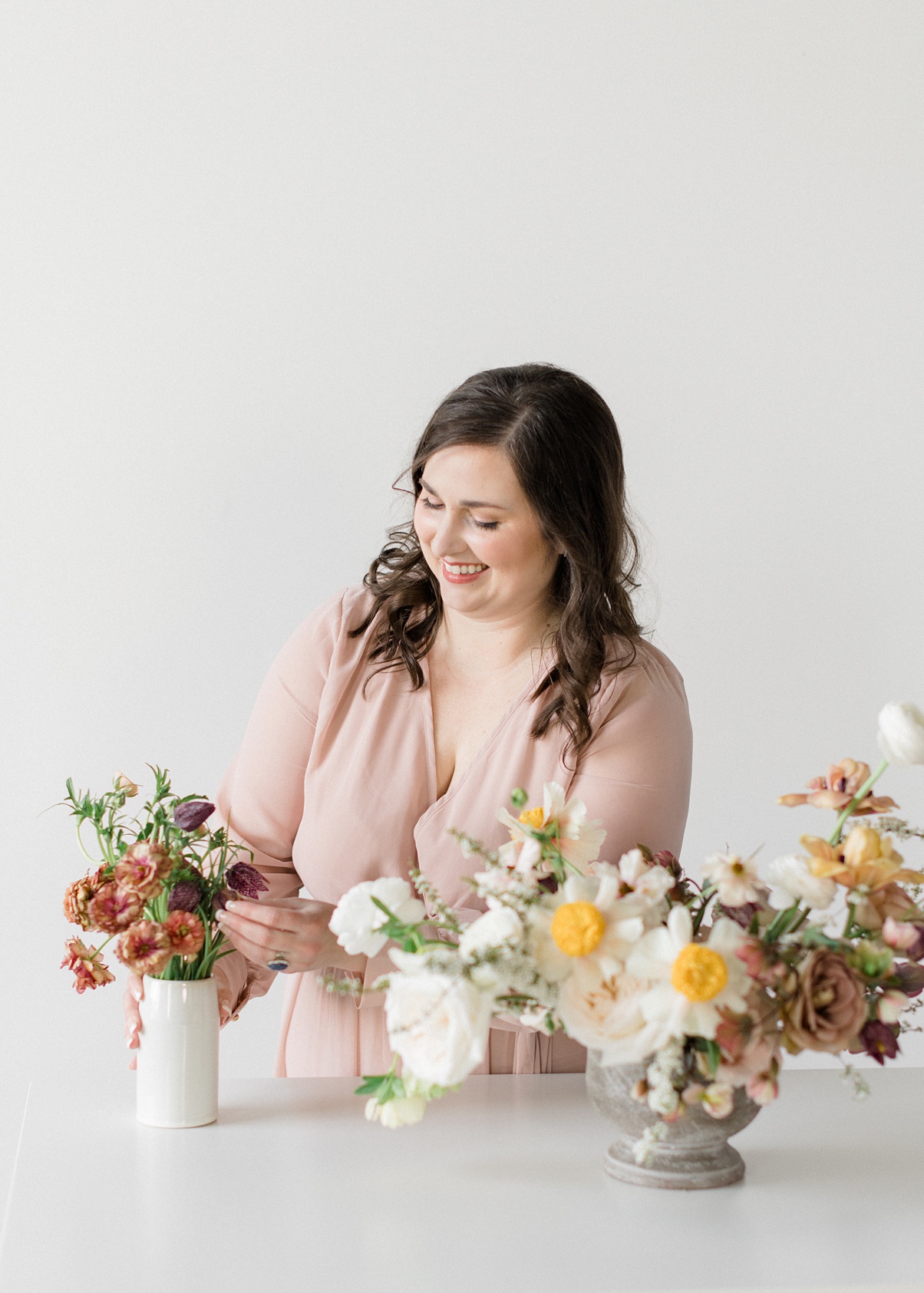 Seattle-Wedding-Florist-Bloom-Poet-Carolyn-Kulb-Arranging Seattle wedding florist and owner of Bloom Poet, Carolyn Kulb, stands at a table arranging flowers