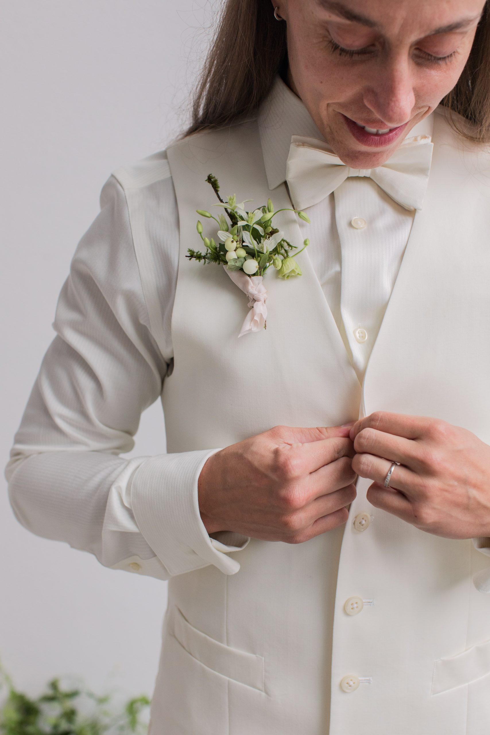 Modern-White-Wedding-Buttoning-Vest A queer bride buttons her vest before the wedding ceremony