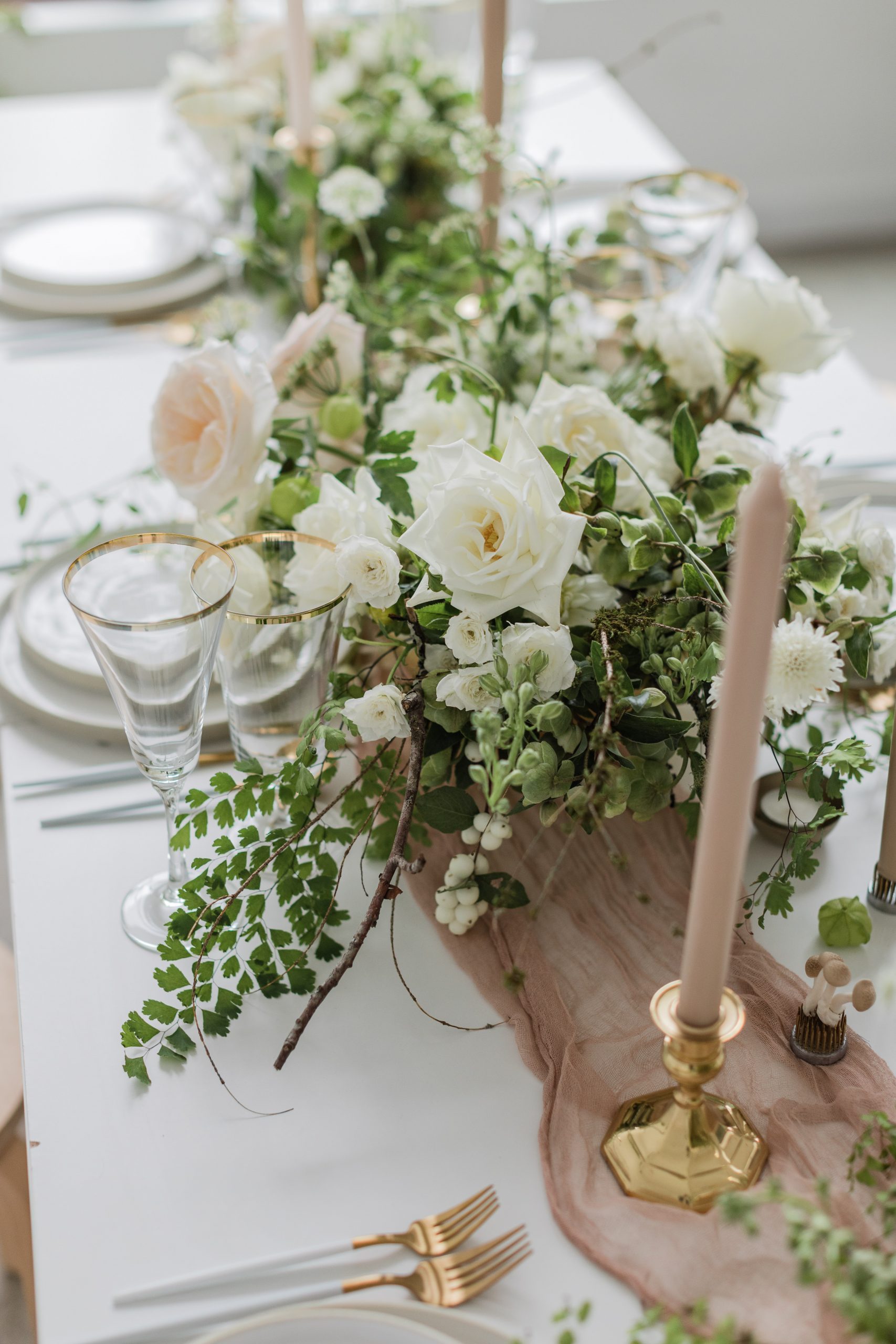 Modern-White-Wedding-Long-Table-Floral-Arrangement A long white wedding table with white florals, a neutral table runner, candles, and place settings
