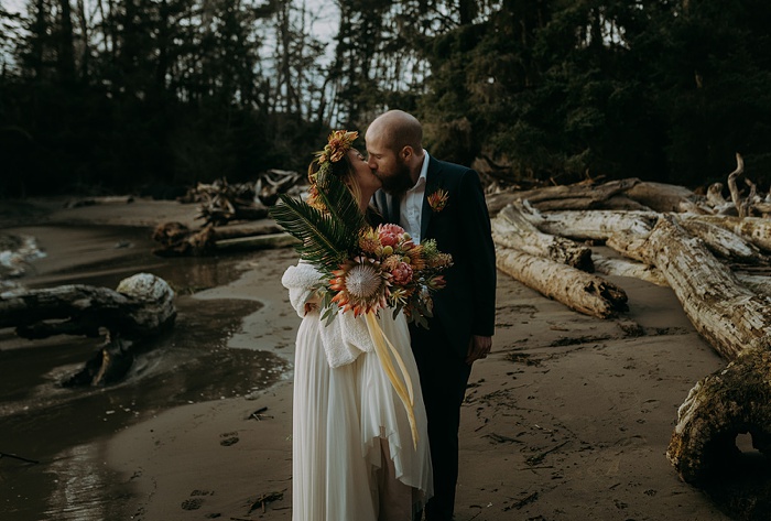 The couple kiss on the beach after their wedding ceremony