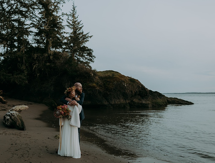 The couple embracing at a beach cove at dusk