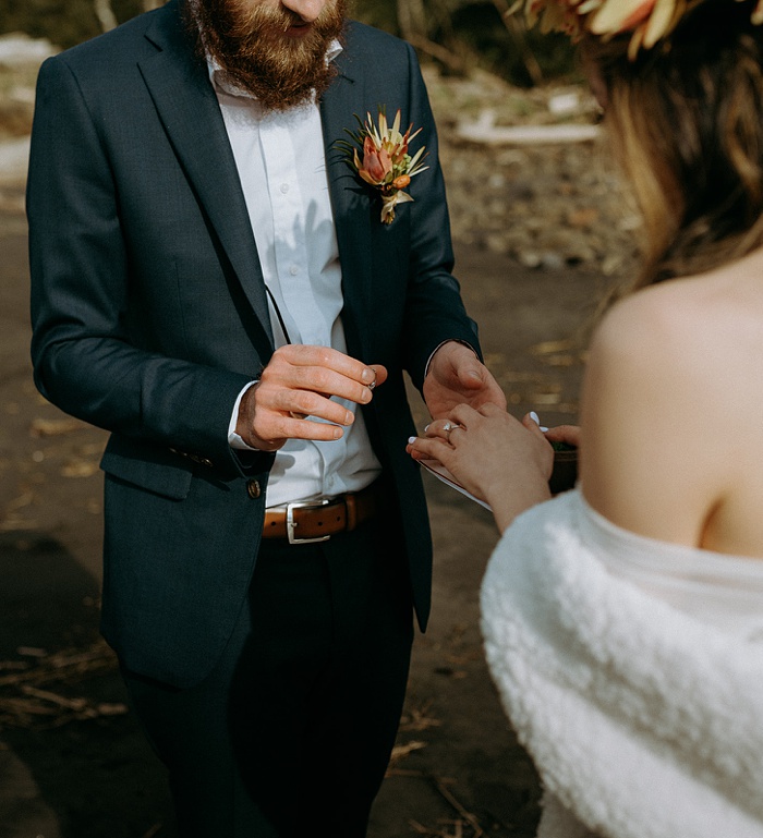 The groom puts the wedding ring on his bride at the beachfront ceremony