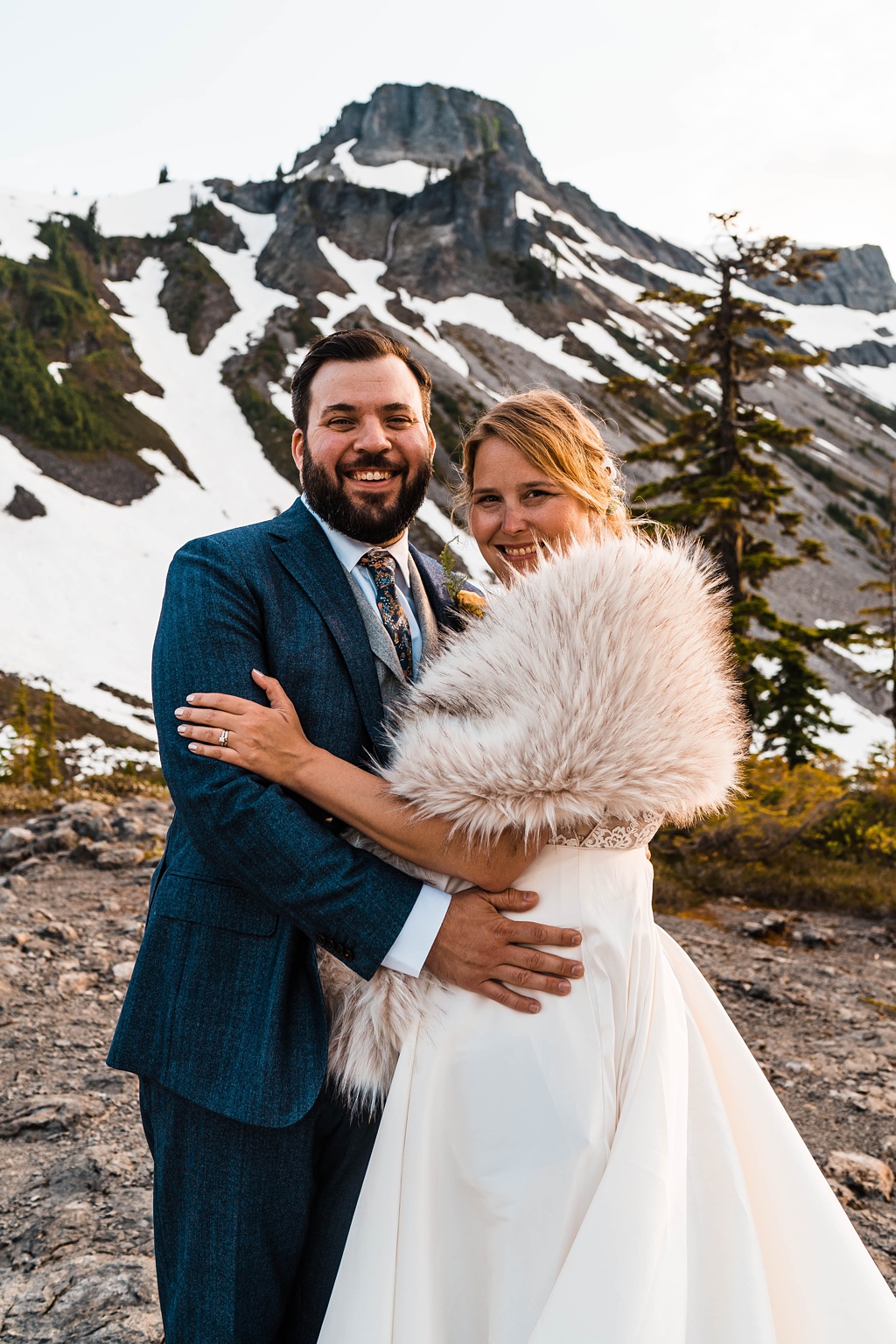 Mountain-Wedding-with-Vibrant-Summer-Blooms-Fur-Shawl The bride and groom embrace, highlighting the bride's fur shawl