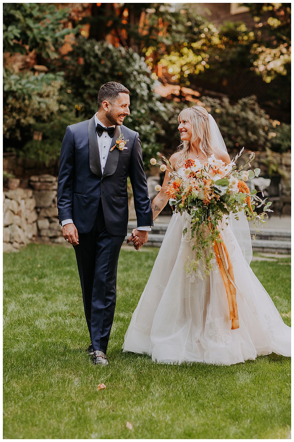 The bride and groom walk across the lawn, holding the bouquet