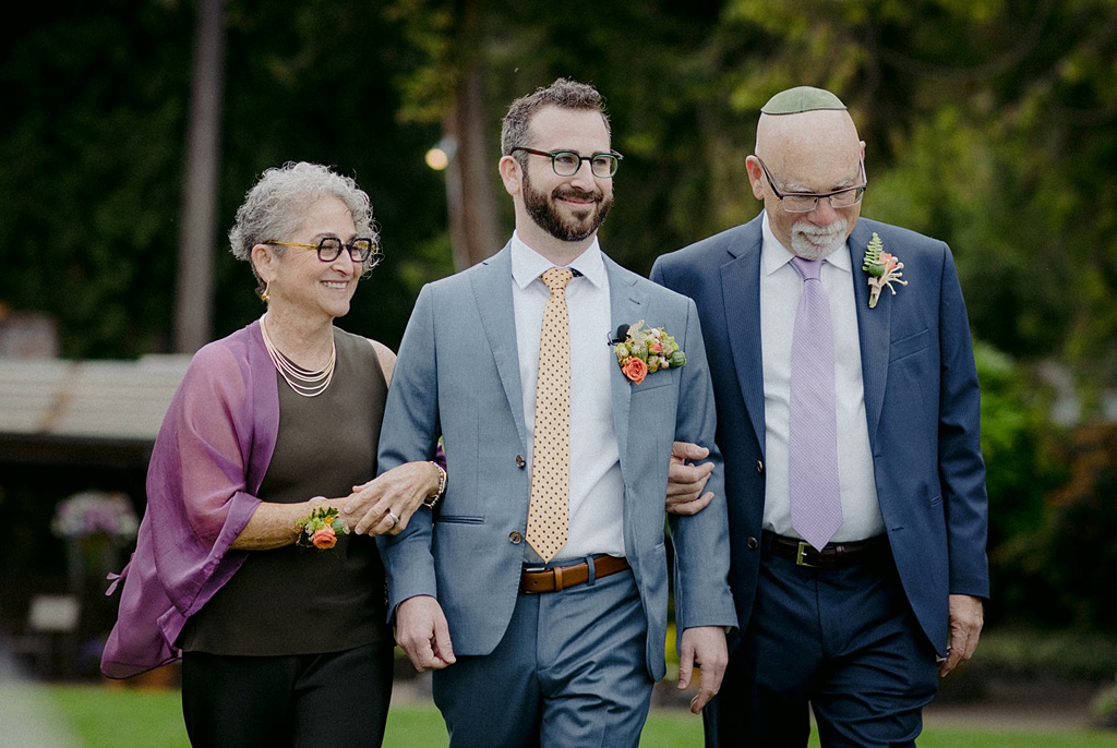 The groom being walked to the ceremony at a Kiana Lodge wedding